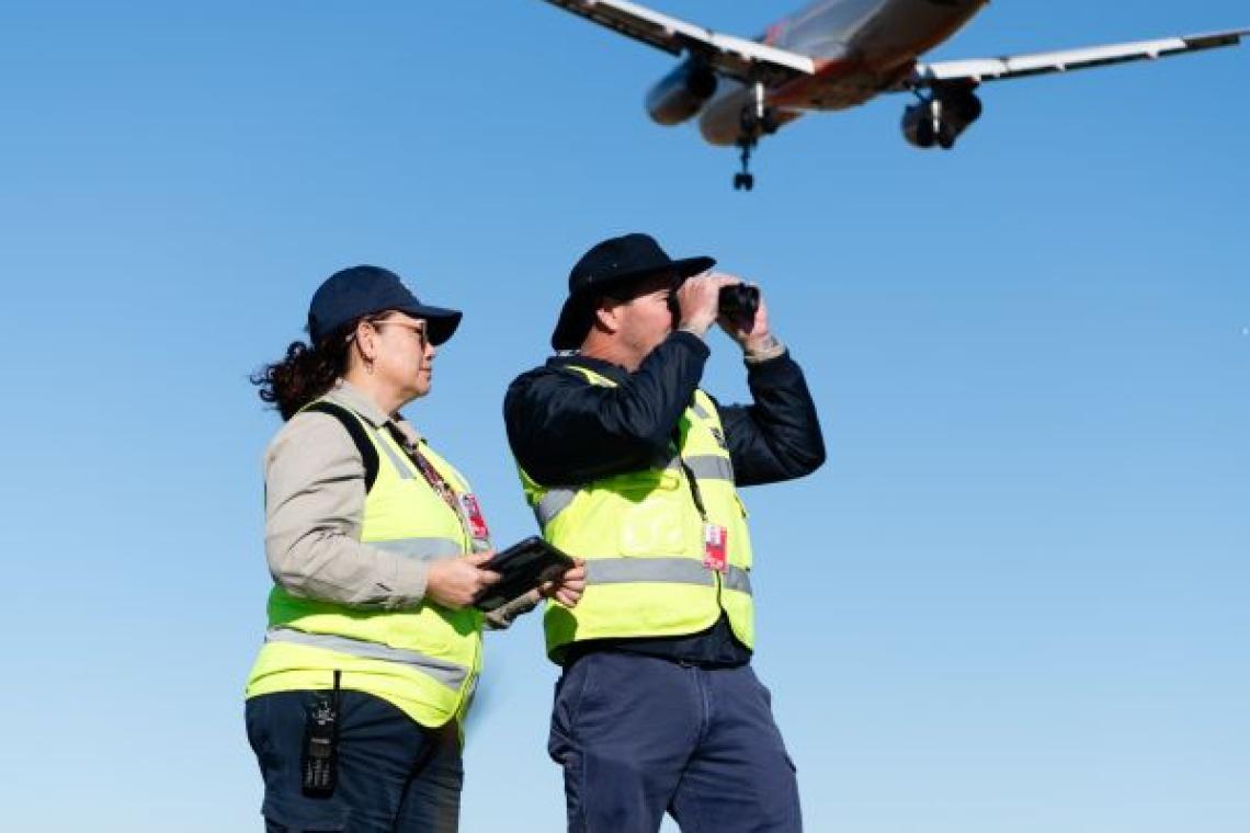 Two airside officers with a Jetstar plane flying overhead Two airside officers with a Jetstar plane flying overhead