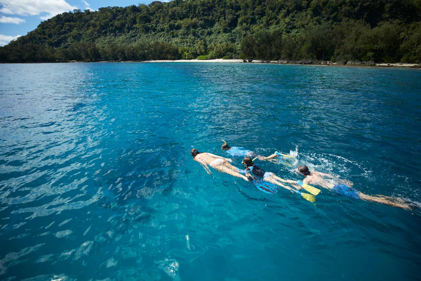 A family snorkelling in blue water off the coast of Vanuatu