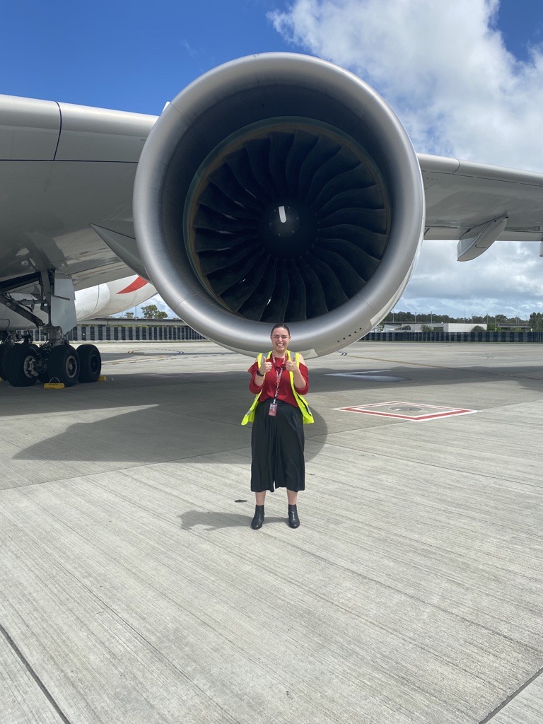 Arabella standing in front of plane turbine