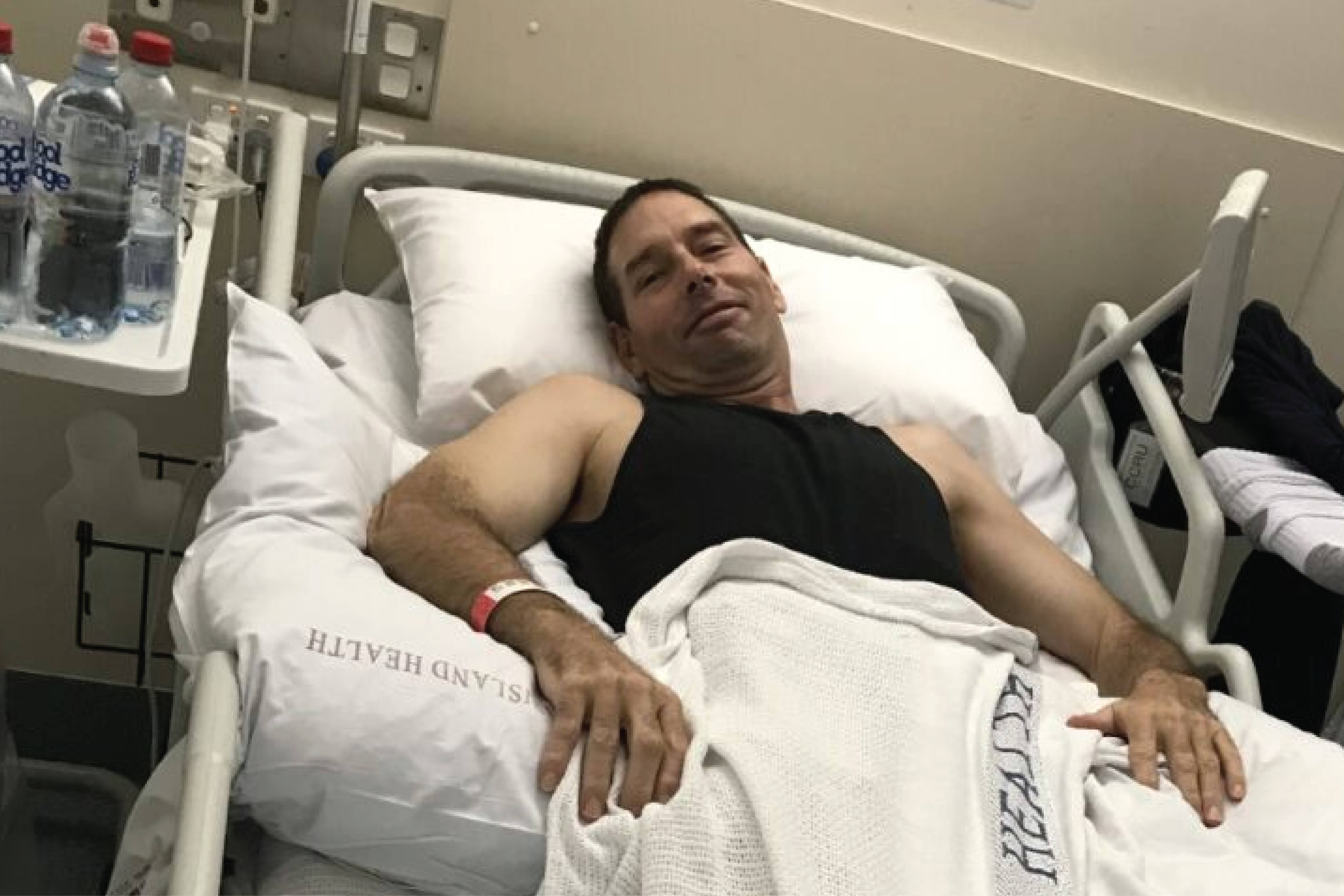 Glenn lying in a hospital bed