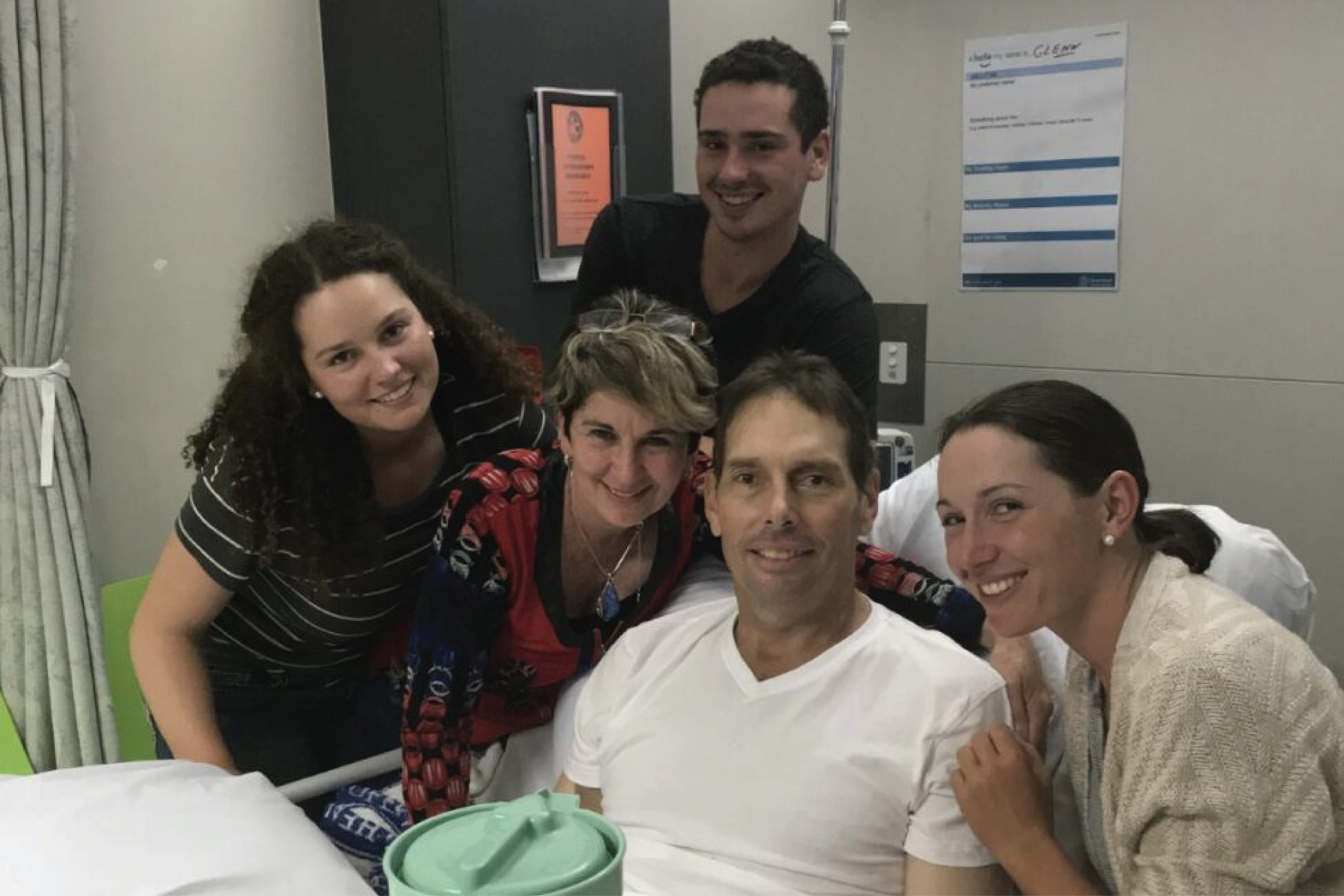 Glenn surrounded by family and friends in his hospital bed