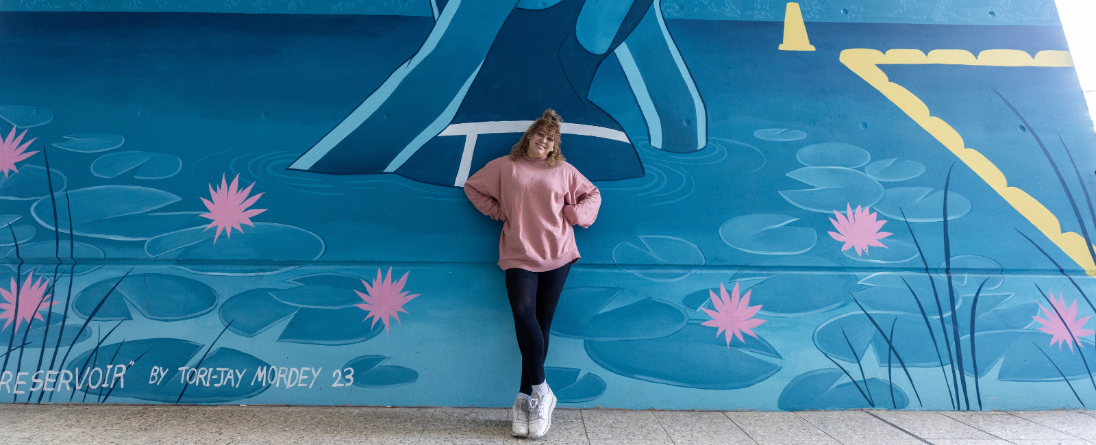 Tori-jay Mordey standing in front of her Enoggera Reservoir artwork
